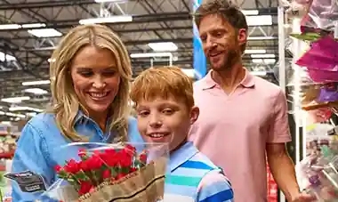 Smiling family choosing red flowers at the supermarket.
